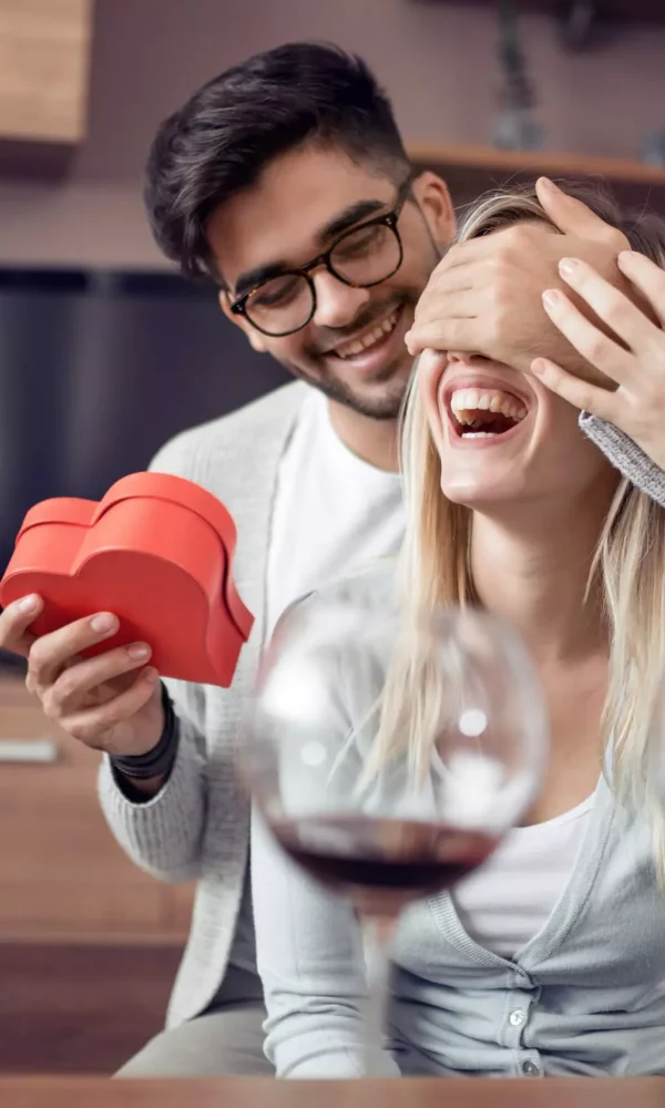 Man presenting gift to woman at home during romantic meeting.